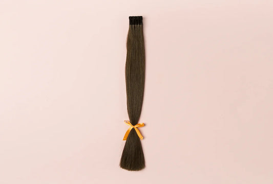 Tom Gold Hair training strands — practice weft of brown hair extensions with gold ribbon on pink background